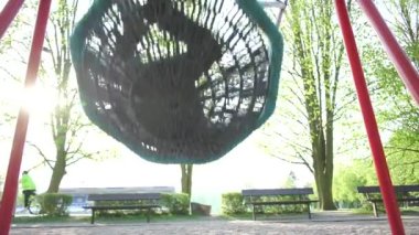 Çocuk şehir parkında salıncakta sallanıyor.