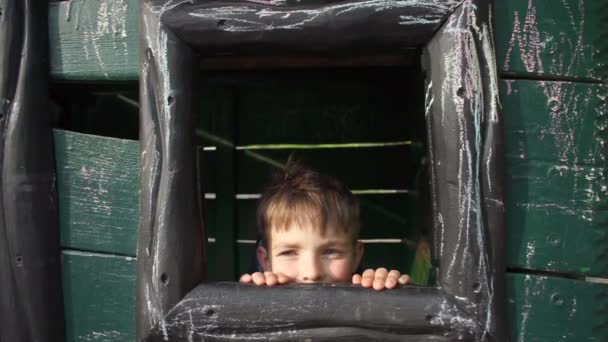 Niño escondido detrás de una ventana de madera — Vídeos de Stock