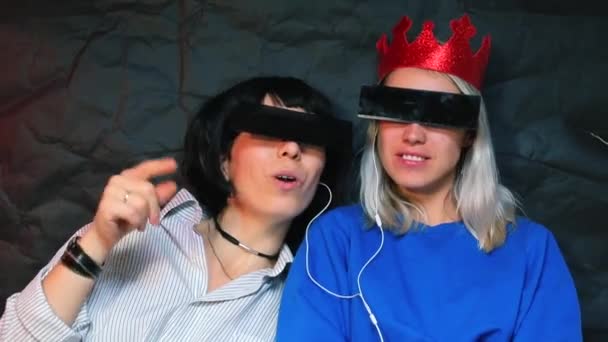 Two lesbians at a bachelorette party listening to music with headphones. — ストック動画