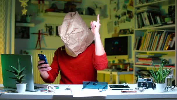 Бізнесмен в червоному одязі з паперовою сумкою його голова сидить за столом в офісі — стокове відео