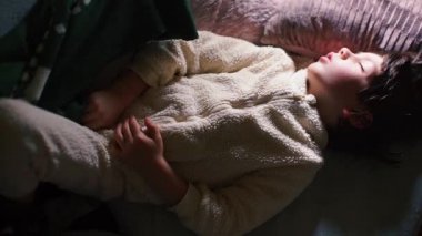 Yatakta beyaz pijamalı, uykulu bir çocuğun portresi..