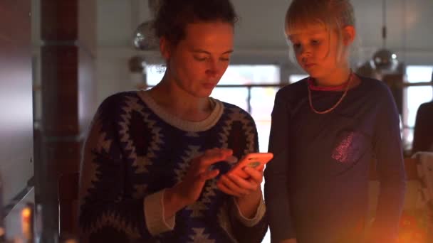 Une femme avec une fille utilise un smartphone le soir . — Video