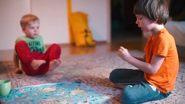 Två pojkar sitter på golvet och spelar brädspel.. — Stockvideo