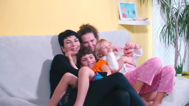 Två partners med en son och dotter sitter på soffan. — Stockvideo