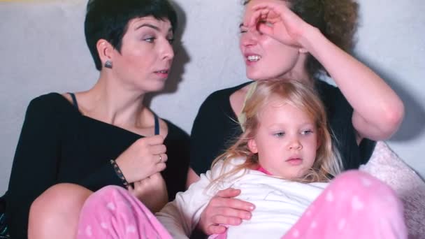 Dos chicas con una hija están sentadas en un sofá en un hotel . — Vídeos de Stock