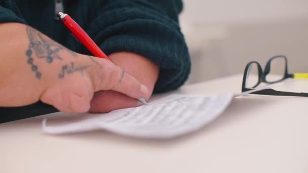 Un homme sans mains écrit du texte au stylo sur papier . — Video