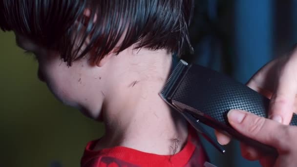 El peluquero corta el pelo en el cuello del niño con una máquina . — Vídeos de Stock