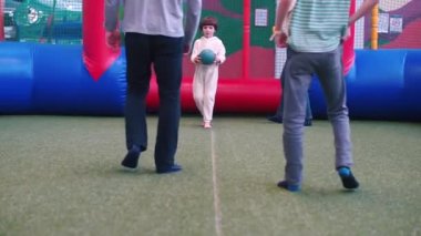 Beyaz pijamalı bir çocuk oyun alanında futbol oynuyor..