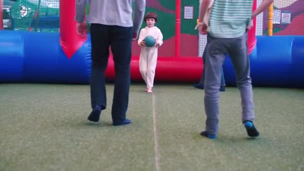 Ein Junge im weißen Pyjama beim Fußballspielen auf dem Spielplatz. — Stockvideo