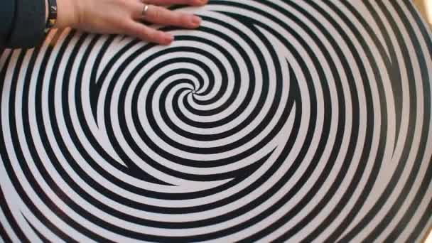 Hand spins a hypnosis spiral on which converging and diverging stripes are drawn — Stock Video