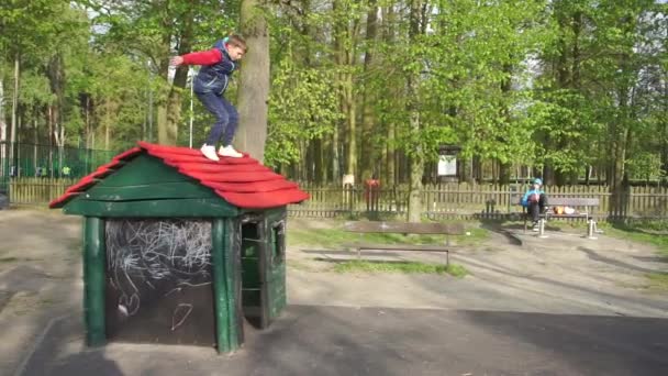 Menino pulando do telhado de uma casa de crianças — Vídeo de Stock