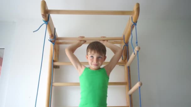 Boy does an exercise on the horizontal bar in the childrens gym at school — Stock Footage Boy does an exercise on the horizontal bar in the childrens gym at school Stock Footage