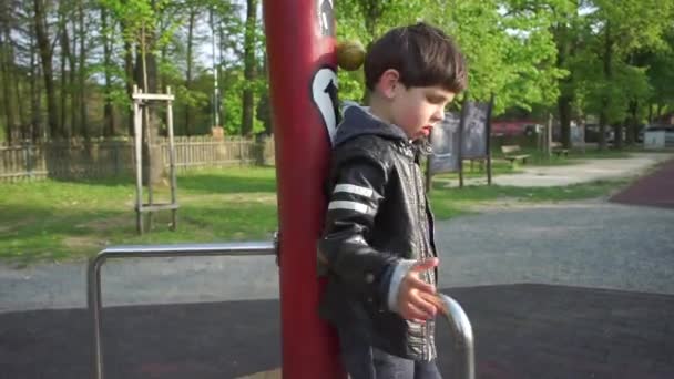 Дети крутятся на карусели на школьной площадке — стоковое видео