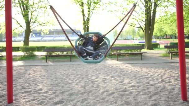 Menino experiências em um childrens balanço no escola playground — Vídeo de Stock