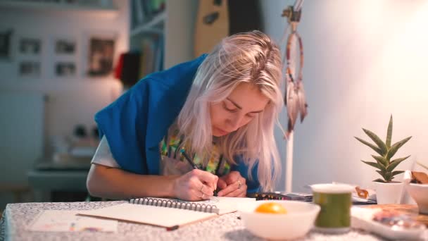 Girl draws a picture on paper sitting at the table. — Stock Video