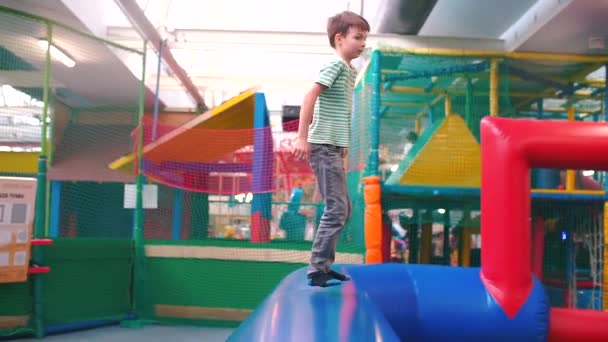 O menino pula em um travesseiro inflável no centro de entretenimento . — Vídeo de Stock
