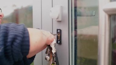 Eli olmayan bir adam anahtarla kapıyı açar..