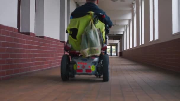 Un uomo in sedia a rotelle cavalca lungo un lungo corridoio — Video Stock