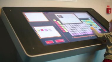 Bir çocuk büyük bir vitrinin yanında duruyor, elektronik gıda alışverişi yapıyor.. 