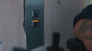 Eli olmayan engelli biri asansör çağırma düğmesine basar..