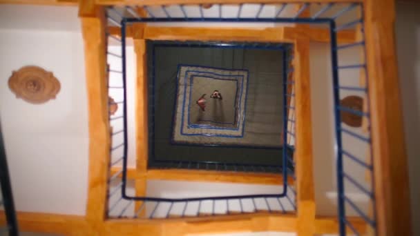 两个男人在镜子天花板上的倒影 围绕着一个正方形的螺旋形楼梯. — 图库视频影像