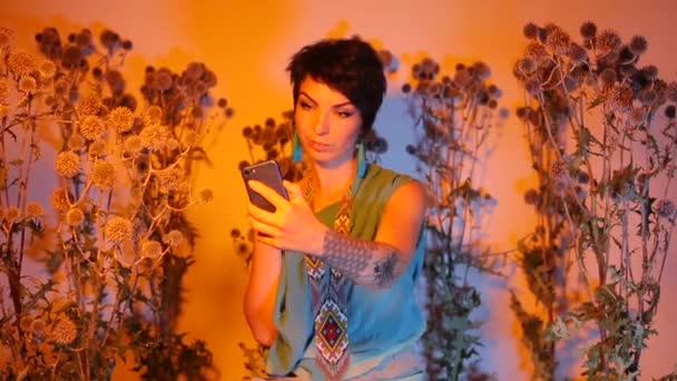 A girl poses and takes photos on a smartphone in wild prickly plants. — Stock Video