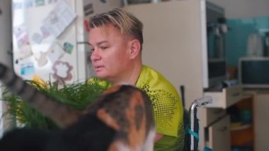 Elleri olmayan engelli bir kadın evdeki masada kedisiyle oynuyor..