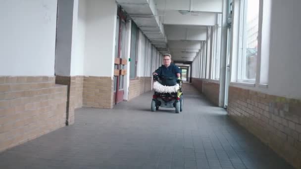 Un uomo sulla sedia a rotelle sta guidando lungo un lungo corridoio . — Video Stock