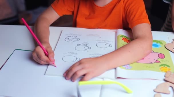 Primer plano, el niño dibuja con lápiz sobre papel en el aula — Vídeos de Stock