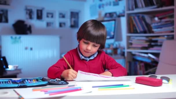En pojke sitter vid ett bord, ritar en bild — Stockvideo