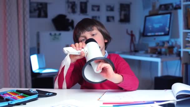 Мальчик исследует мегафон в своих руках, а затем начинает говорить в него — стоковое видео