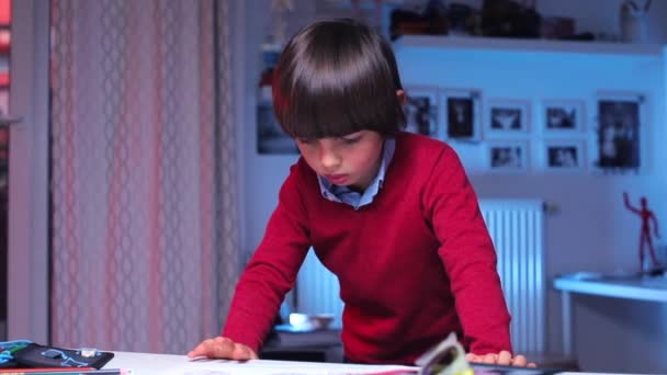 Wesoły chłopiec stoi przy stole, uważnie się rozgląda — Wideo stockowe