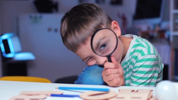 Intelligent garçon regarde avec un oeil dans une loupe — Video