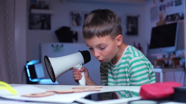 El niño grita en un megáfono, luego examina un pequeño tema — Vídeo de stock