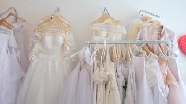 Много свадебных платьев висит на вешалках — стоковое видео
