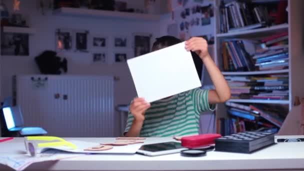 A schoolboy in his hands shows a white sheet of paper, twists it — Stock Video