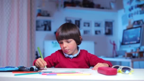 Solitaire écolier dessine à une table, regarde la caméra — Video