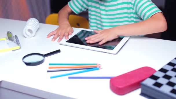 Primo piano, un adolescente a un tavolo strofina uno schermo di tablet — Video Stock