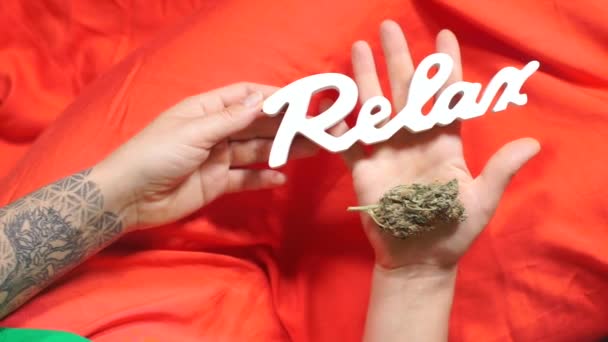 Houdt in haar hand een marihuana knop en de inscriptie ontspannen — Stockvideo