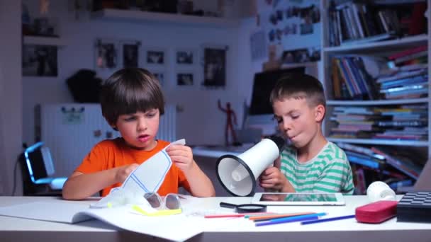 两个小孩坐在桌旁，一个小孩尖叫，另一个小孩剪纸 — 图库视频影像