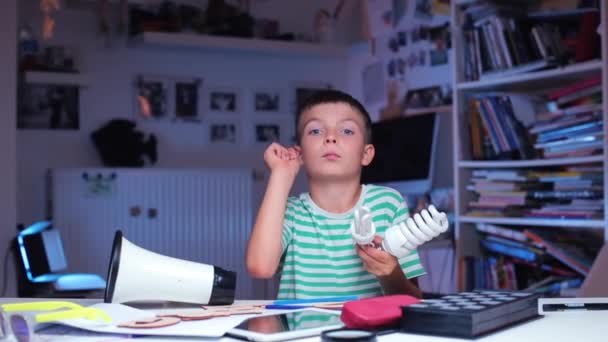 Teenager sedí u stolu ve škole, hraje si s žárovkami — Stock video
