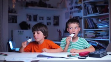 İki okul çocuğu masada otururken dondurma yiyorlar.