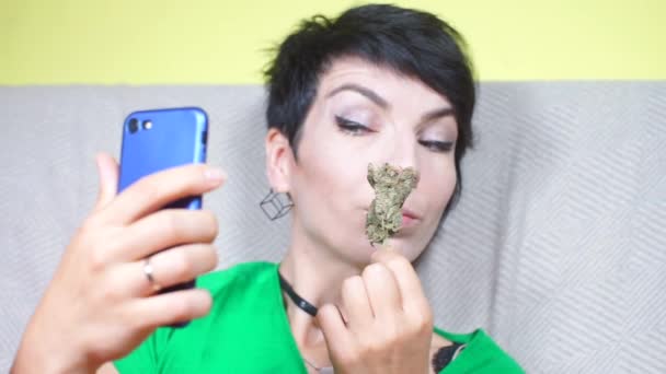 Kız akıllı telefondan fotoğraf çekiyor, esrar çekiyor, tıbbi marihuana içiyor. — Stok video