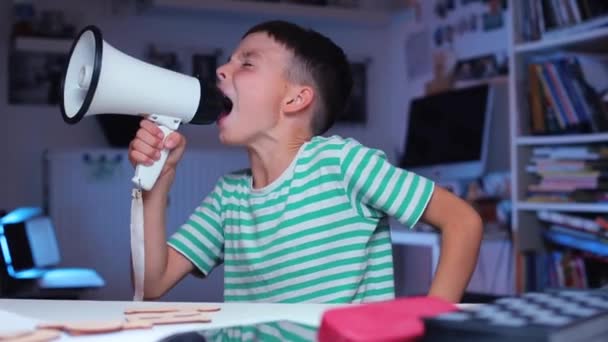 De schooljongen aan tafel schreeuwt in een megafoon, en begint dan te schieten — Stockvideo