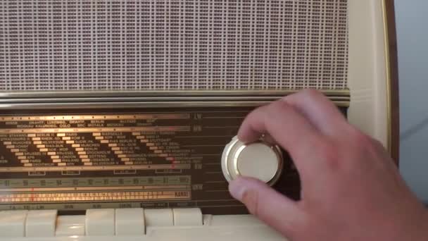 Человек крутит ручку радиоприемника, мелодии в радиоволне — стоковое видео