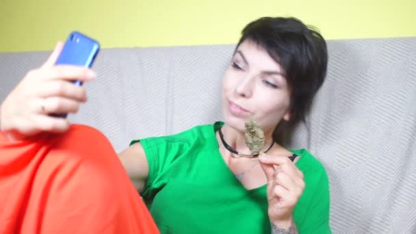 Dívka je vyfocena na smartphonu s konopným pupenem — Stock video