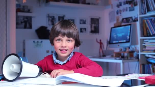 Happy child sitting at a table with a megaphone — Stock Video