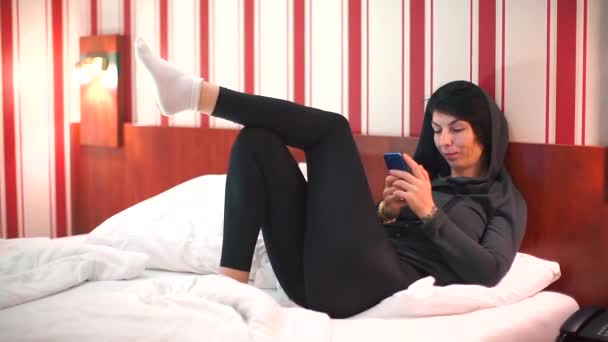 La fille assise sur le lit croisé ses jambes . — Video