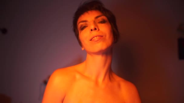 En tårdrypande transpersoner står i orange ljus. — Stockvideo