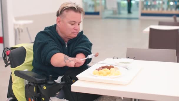 Gehandicapte man, kantoormedewerker zittend aan een tafel in een restaurant, lunchend. — Stockvideo